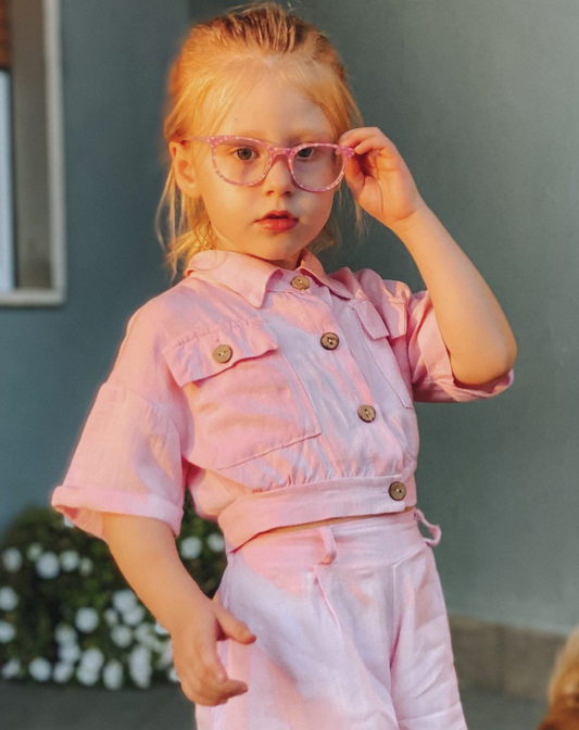 A girl wearing pink glasses in the sun.