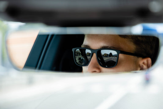 Man wearing Zenottic Jungle sunglasses, black TR90 frame, reflected in car mirror, driving.