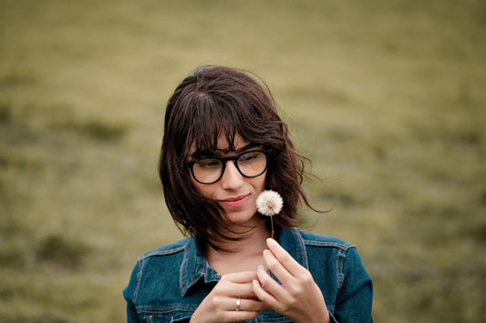 Woman in Zenottic blue light glasses holding dandelion, black plastic frame