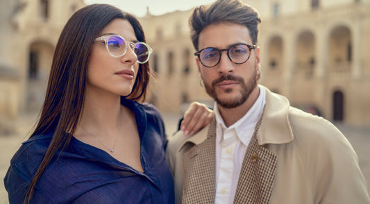 A couple posing outdoors in clear and tortoiseshell round-framed glasses.