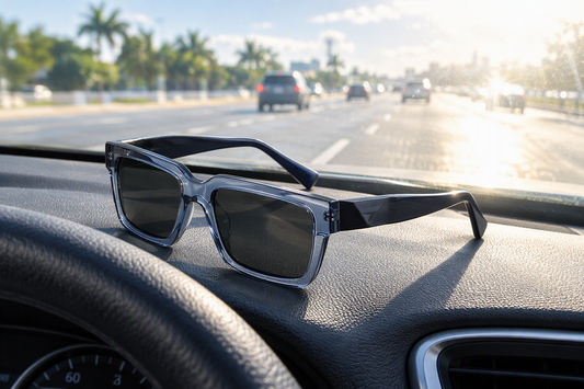 Zenottic rectangular Rx sunglasses with dark lenses sit on a car dashboard facing sunlit highway traffic.